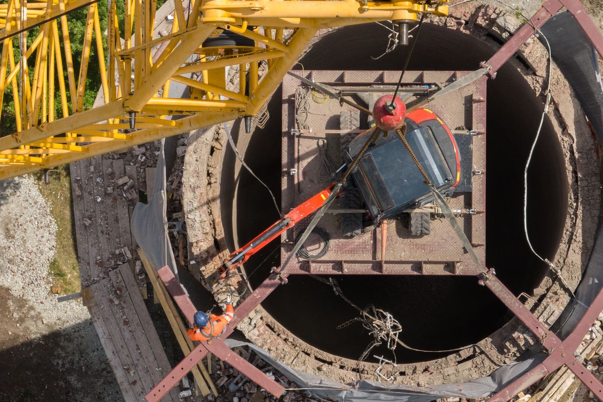 Aerial view of a crane lowering equipment into a large circular structure on a construction site